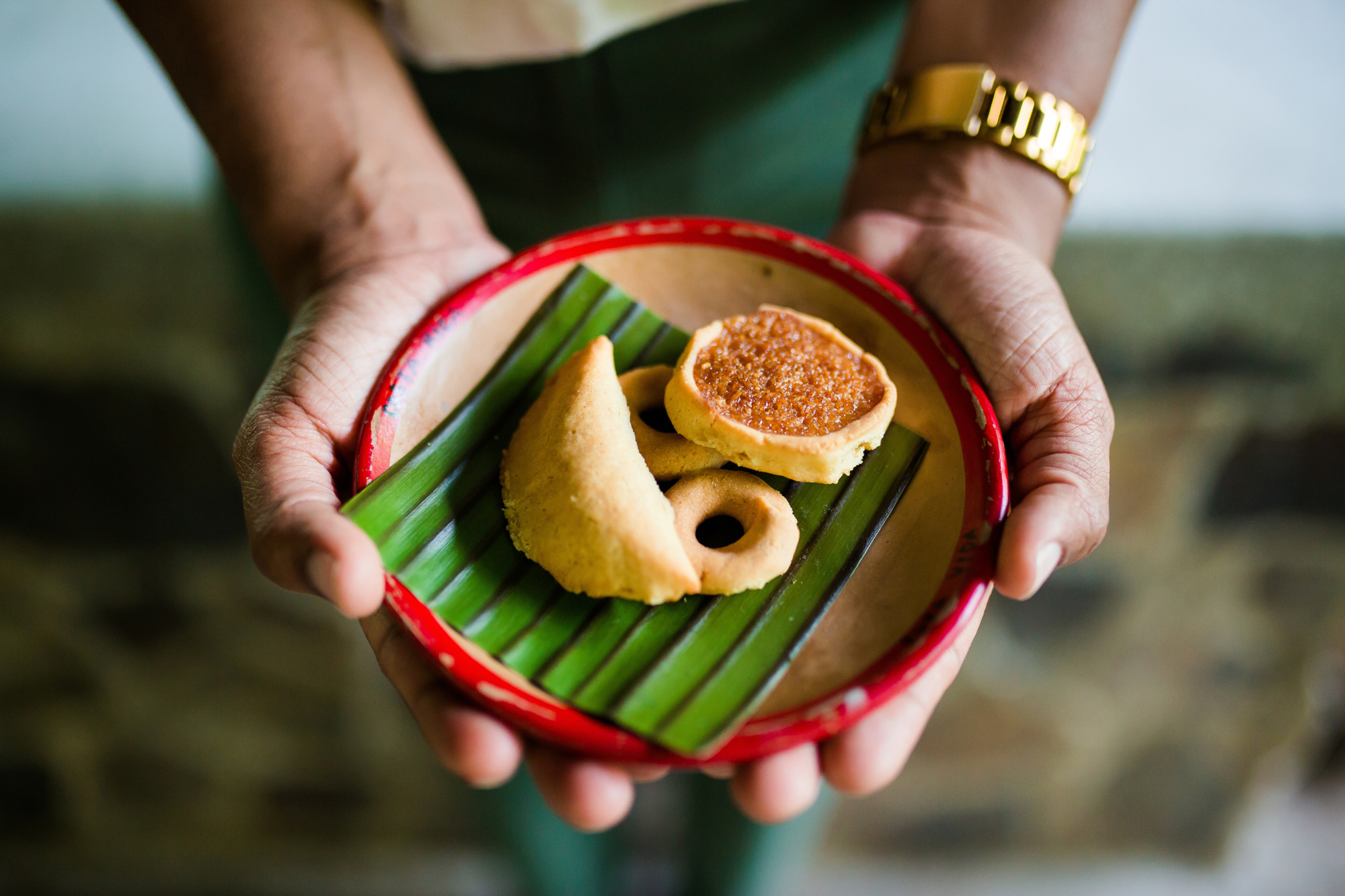 Nexus Nature - 8 Hands holding a plate with assorted pastries on a banana leaf.