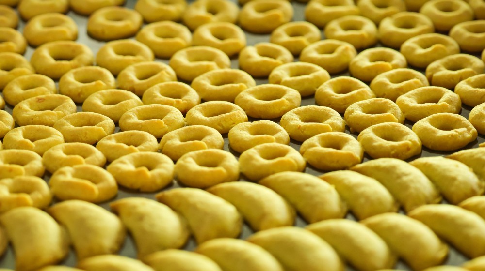 Rows of ring-shaped and crescent-shaped cookies on a baking tray.