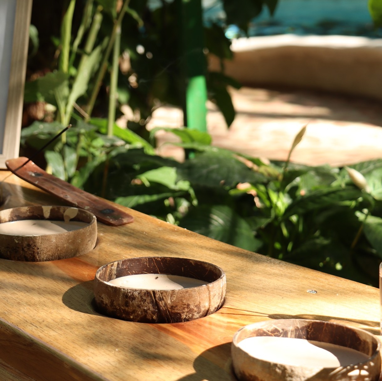 Portavelas de madera con velas sin encender sobre una mesa en un jardín.